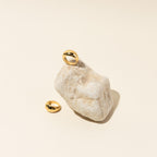 The Bold Dome Ring, showcased on a light stone with another beside it, shines against a beige background.