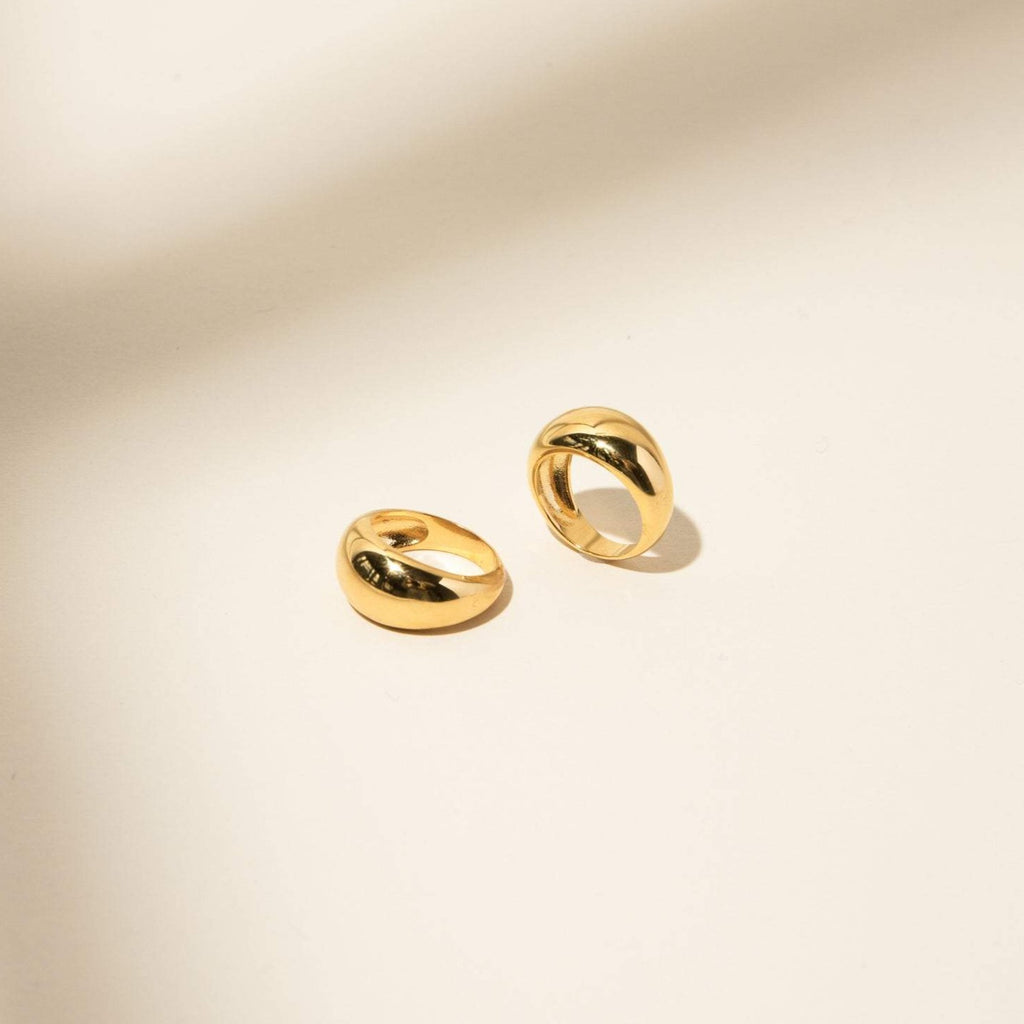Two gold, chunky hoop earrings rest on a light beige surface with soft shadows—perfect to pair with your favorite Bold Dome Ring or stacking rings for a statement look.