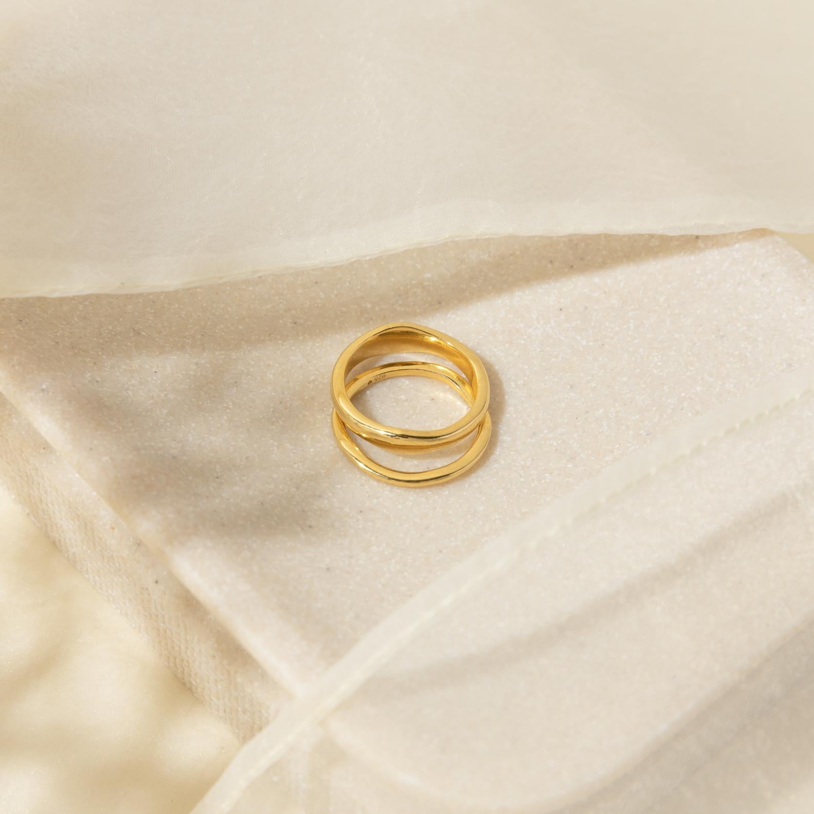 Duo Form Ring Set resting on a soft neutral fabric surface, emphasizing its smooth golden shine.