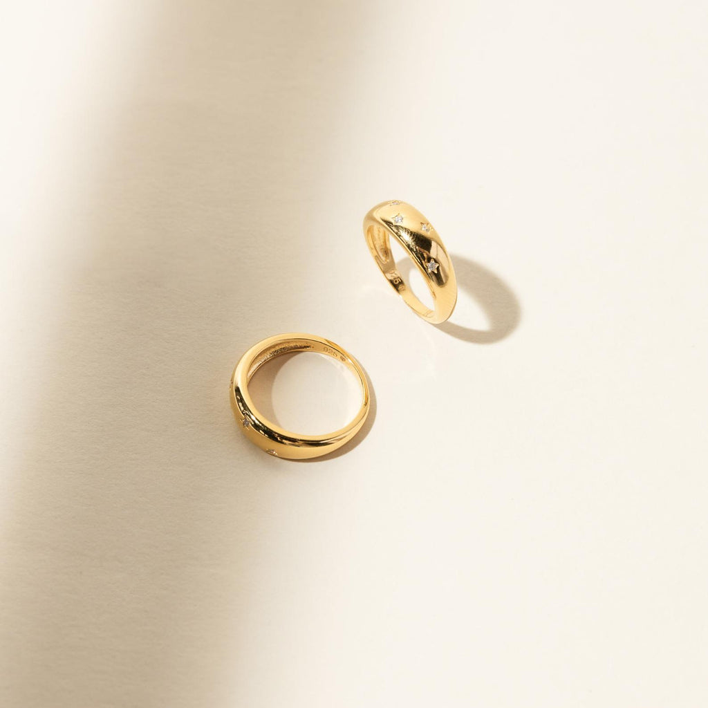 The Star Dome Ring rests on a light beige surface, surrounded by soft shadows and illuminated by bright natural lighting.