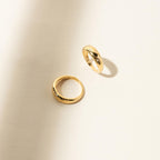 The Star Dome Ring rests on a light beige surface, surrounded by soft shadows and illuminated by bright natural lighting.