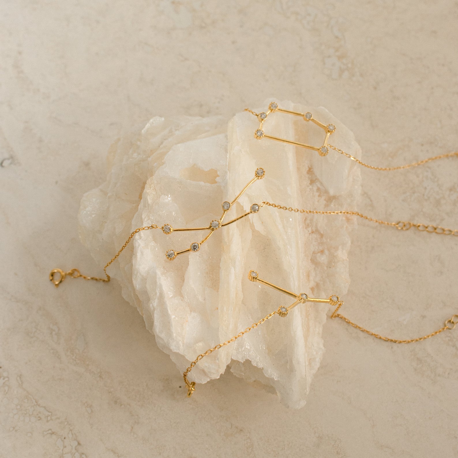 The Constellation Bracelet features a minimal gold design with small crystals, displayed on a white stone background—a unique jewelry piece that brings subtle elegance to any look.