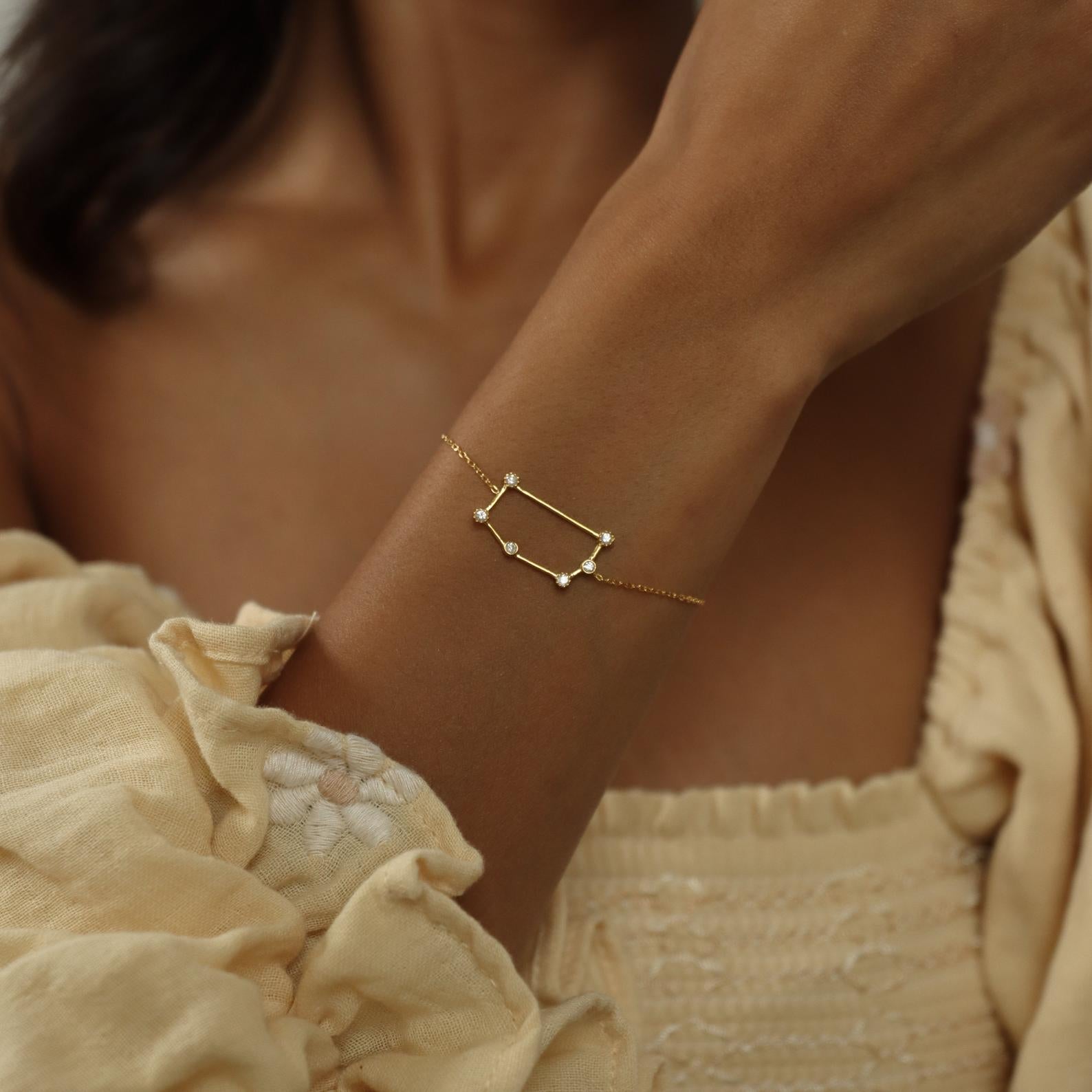 A woman wears the Constellation Bracelet featuring a rectangular pendant, paired with a cream textured blouse for an effortlessly minimal look.