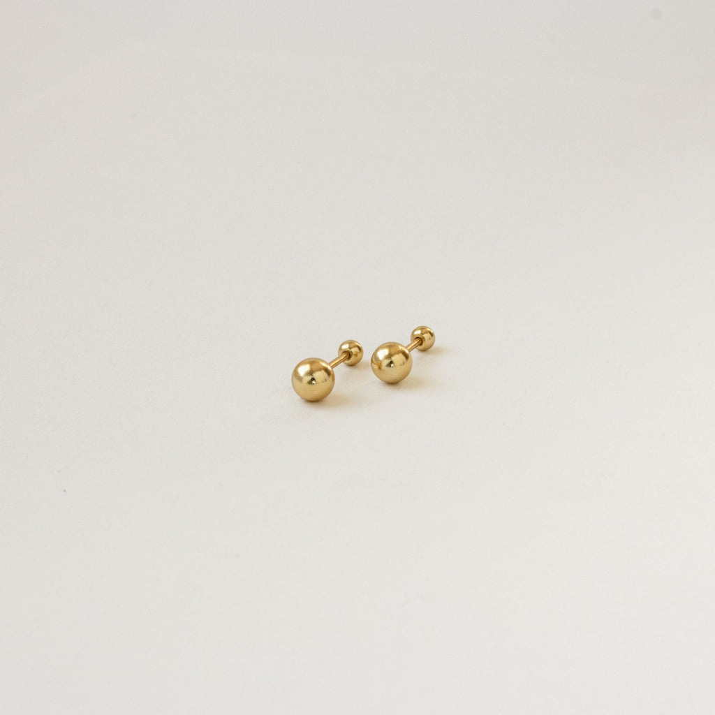 The Hailey Ball Studs are small gold earrings with screw-on backings, ideal for starter earrings, displayed against a plain white background.