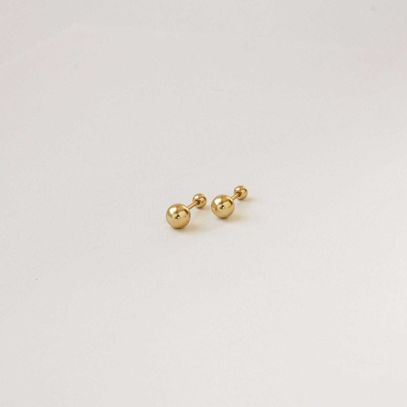 The Hailey Ball Studs are small gold earrings with screw-on backings, ideal for starter earrings, displayed against a plain white background.