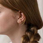 Close-up of a person with braided brown hair wearing Dainty Bar Studs—minimalist earrings ideal for an effortless look.