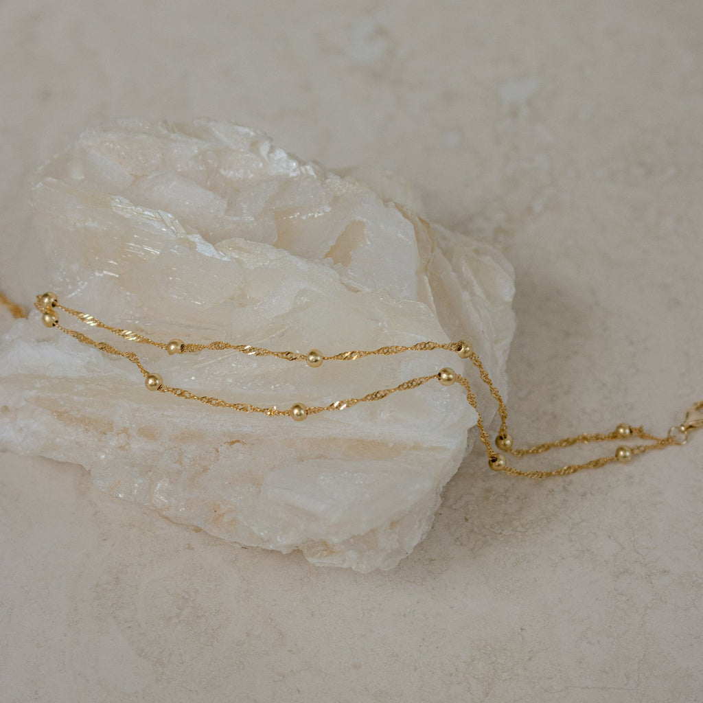 The Duo Bead Chain Bracelet in Sterling Silver features delicate beads, ideal for pairing with a gold chain necklace for a chic and elegant look on any occasion.