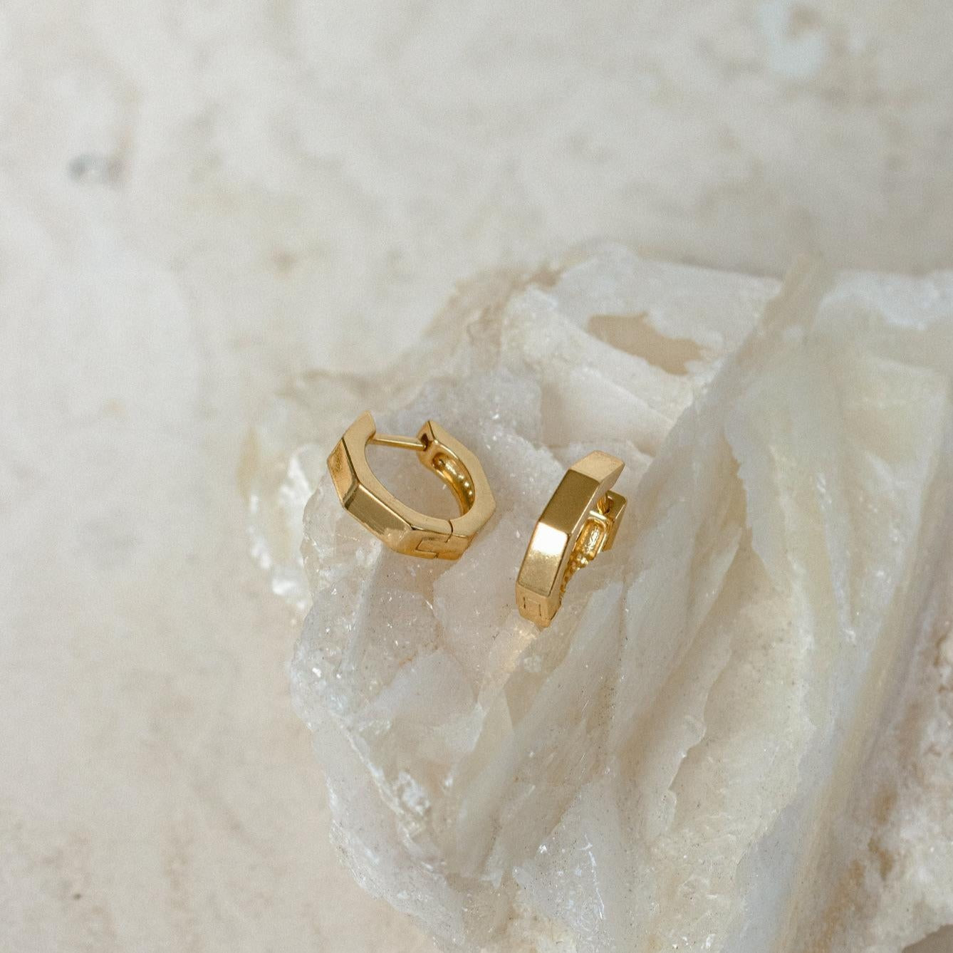 Audrey Huggies displayed on a textured, crystalline white stone surface—an ideal everyday accessory that effortlessly elevates any look.