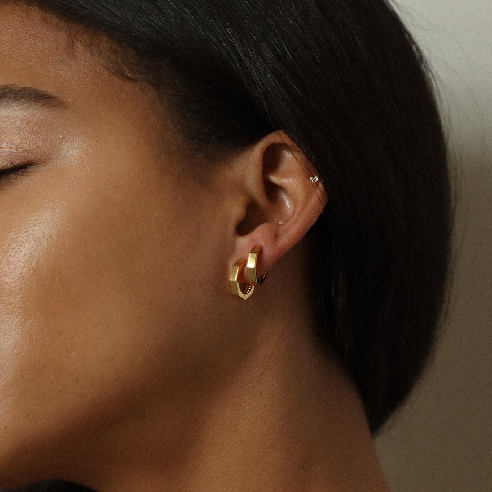 Close-up of a woman wearing Audrey Huggies—gold huggie earrings paired with a small silver stud in her upper ear for an effortlessly chic everyday look.