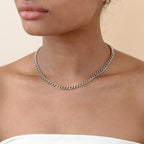 A silver curb chain necklace worn on a model's neck.