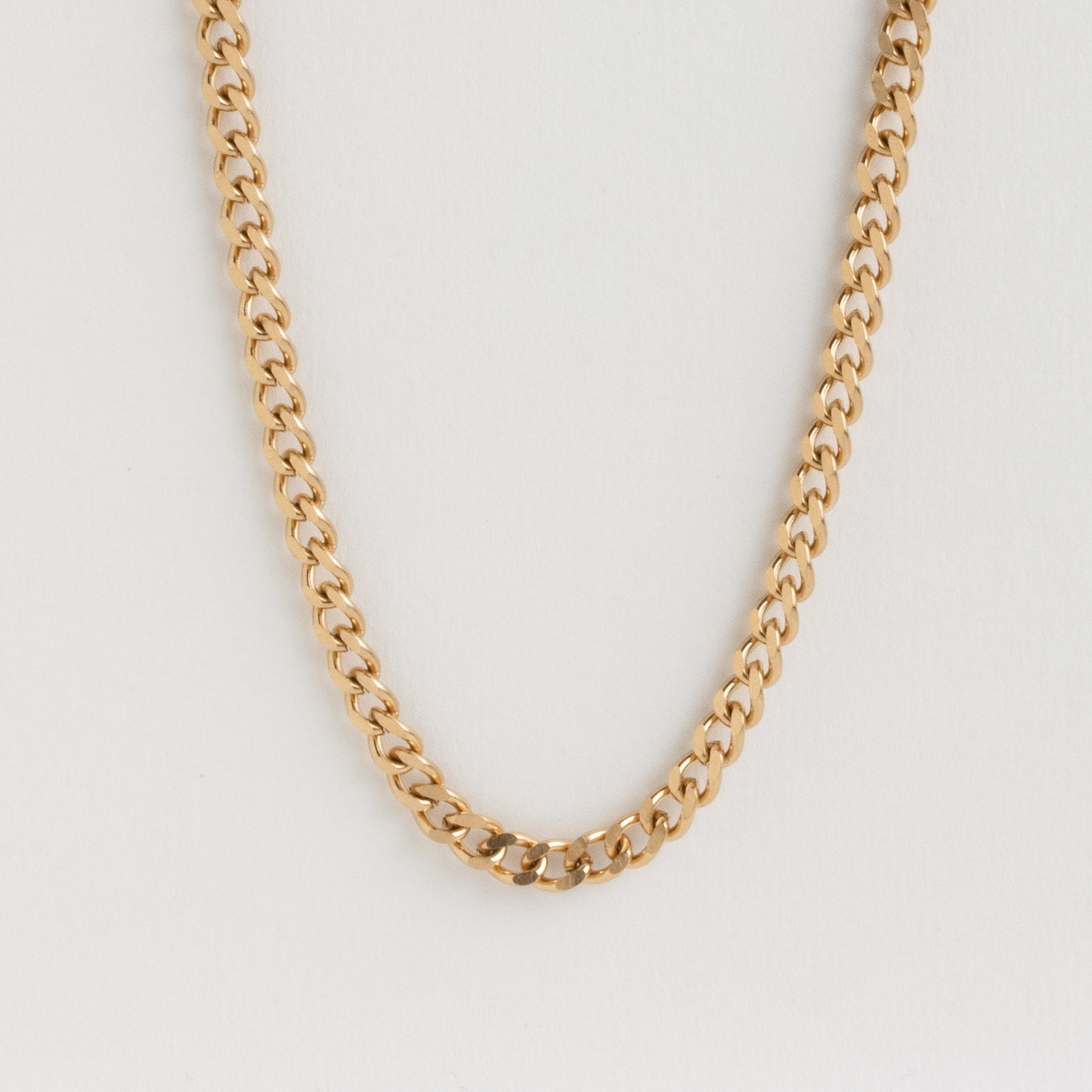Isolated shot of the gold curb chain necklace against a white background.