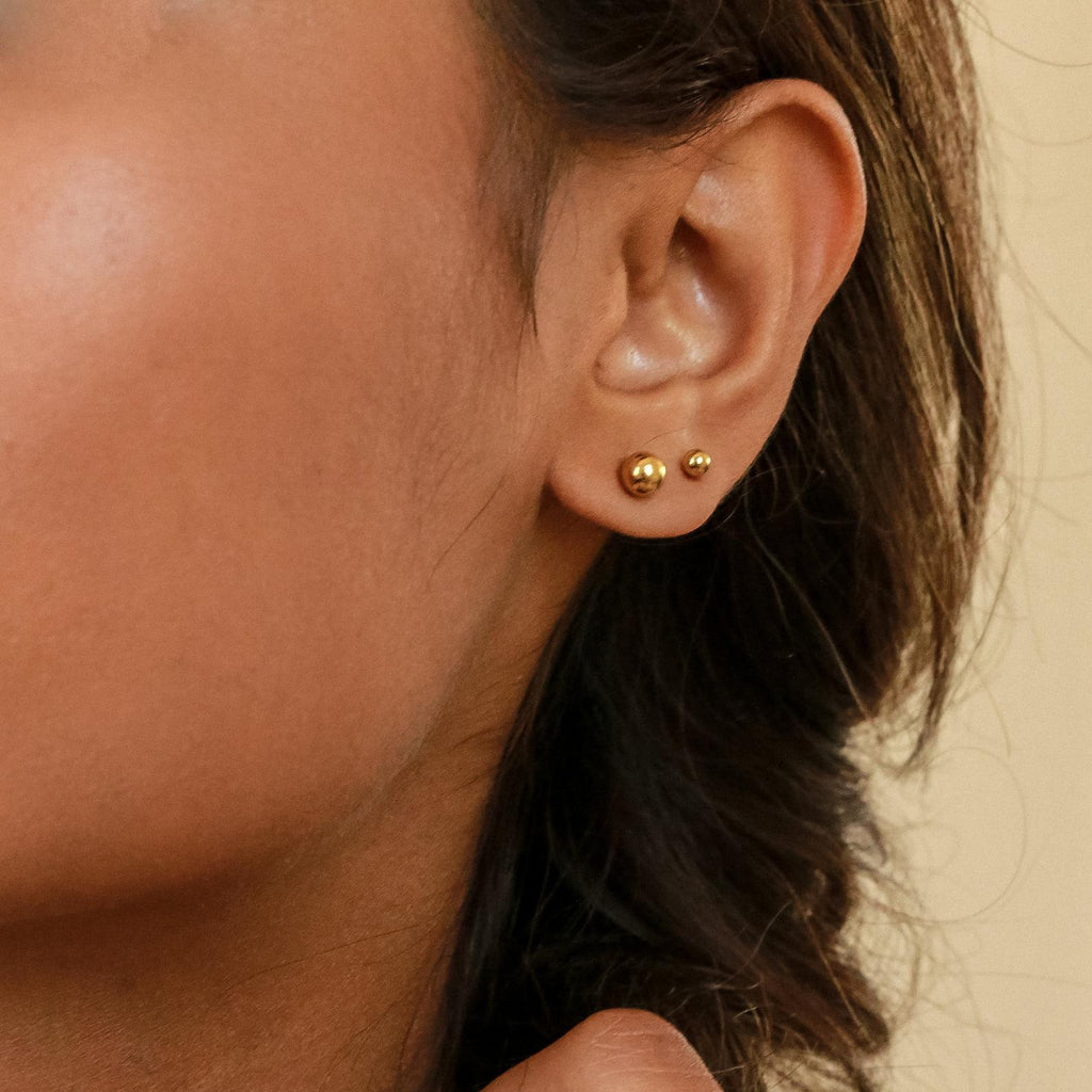 A close-up of a woman's ear wearing Hailey Ball Studs, classic earrings with a secure screw-on backing.