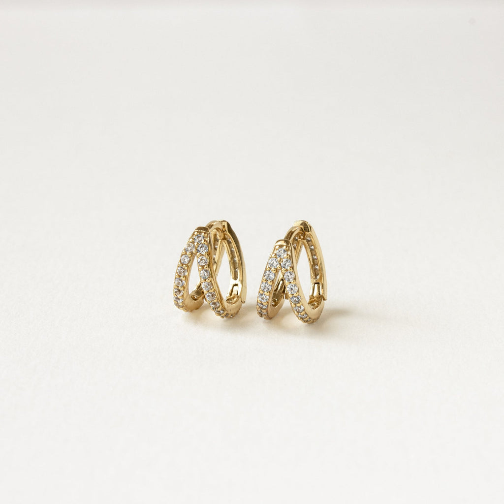 Esther Duo Pave Huggies—gold double hoop earrings with a crisscross design and sparkling crystals, reminiscent of pave huggies, shown on a plain white background.