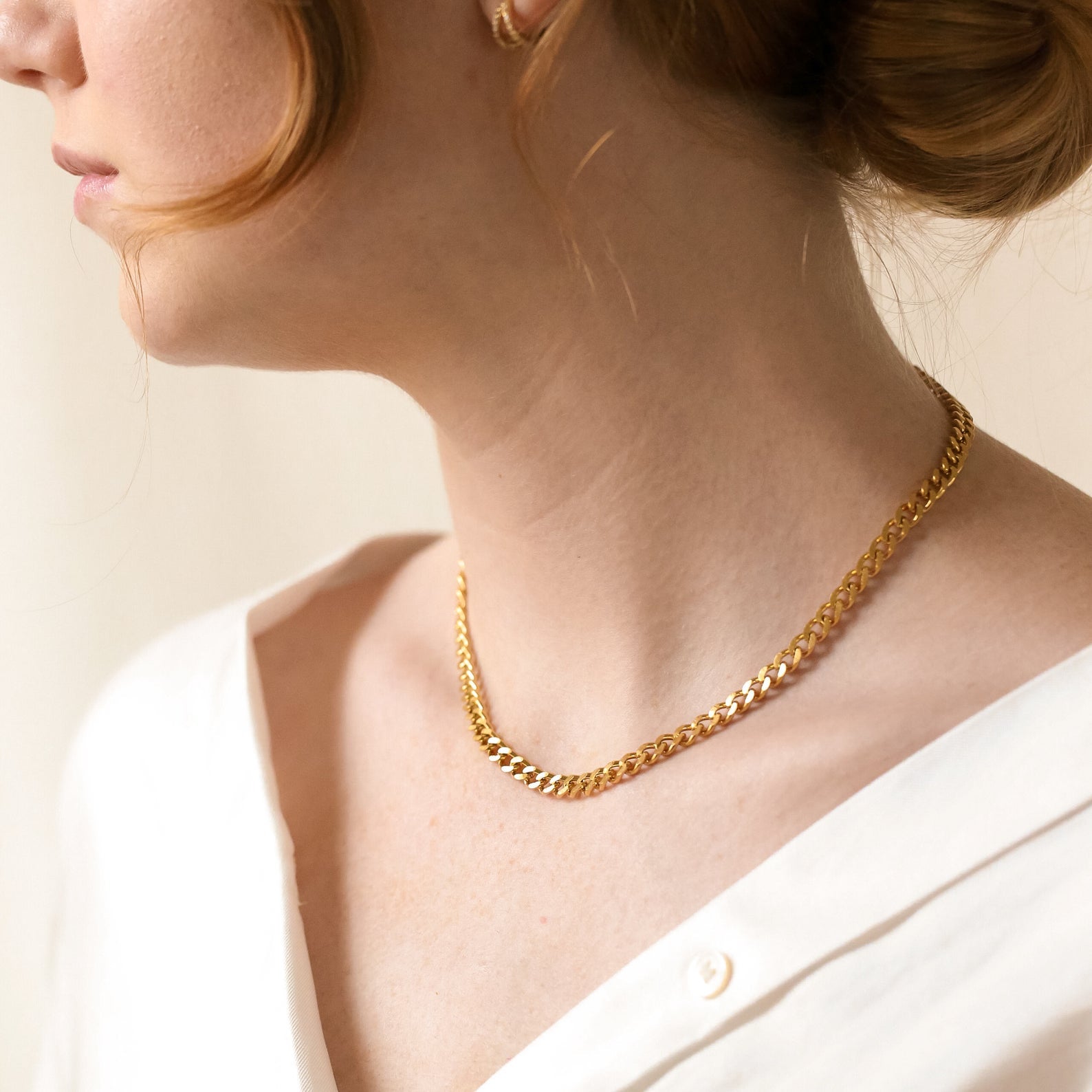 A close-up of the gold curb chain necklace worn on a woman