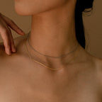 The gold and white gold snake chains worn together as a layered choker look on a model