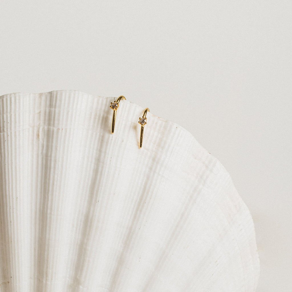 The Rylee Diamond Wire Earrings, a modern pair, displayed elegantly on a white shell.