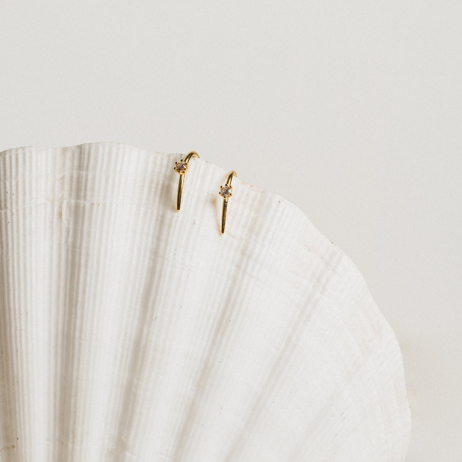 The Rylee Diamond Wire Earrings, a modern pair, displayed elegantly on a white shell.