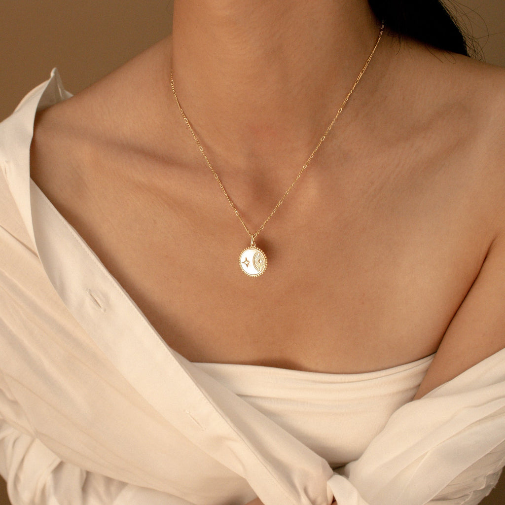A woman models the Gabi Coin Necklace with an off-shoulder white blouse against a neutral backdrop, highlighting the necklace's minimalist elegance.