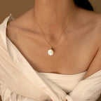 A woman models the Gabi Coin Necklace with an off-shoulder white blouse against a neutral backdrop, highlighting the necklace's minimalist elegance.
