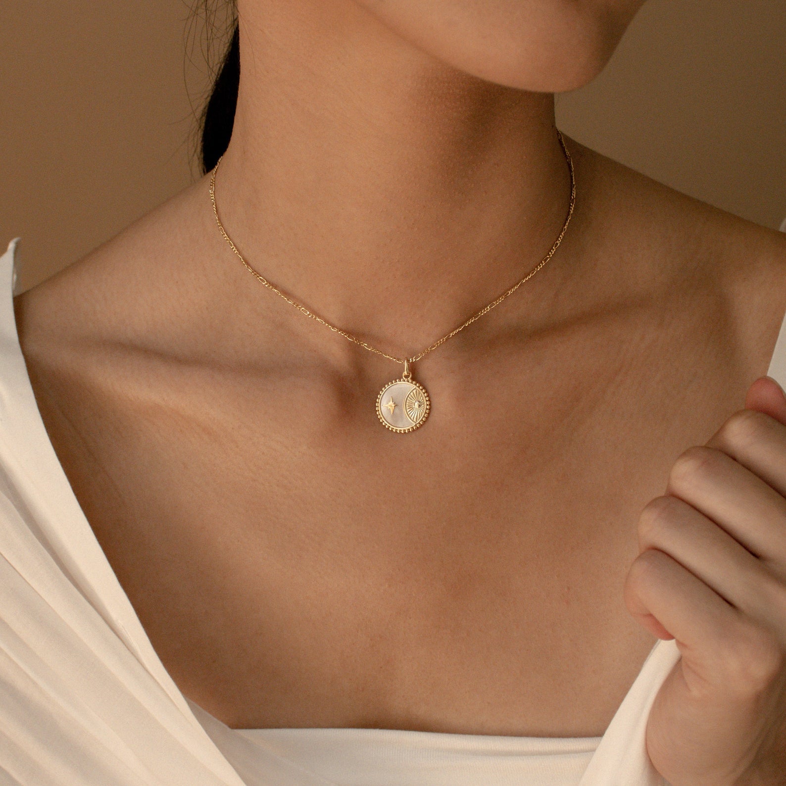 A woman is shown from shoulders to chin wearing a white top and the Gabi Coin Necklace, a minimal gold necklace featuring a round pendant.