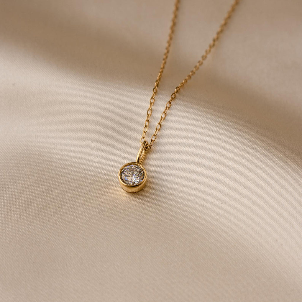 Custom Birthstone Necklace featuring a round pendant, displayed on smooth light beige fabric—an elegant and meaningful jewelry piece for any occasion.