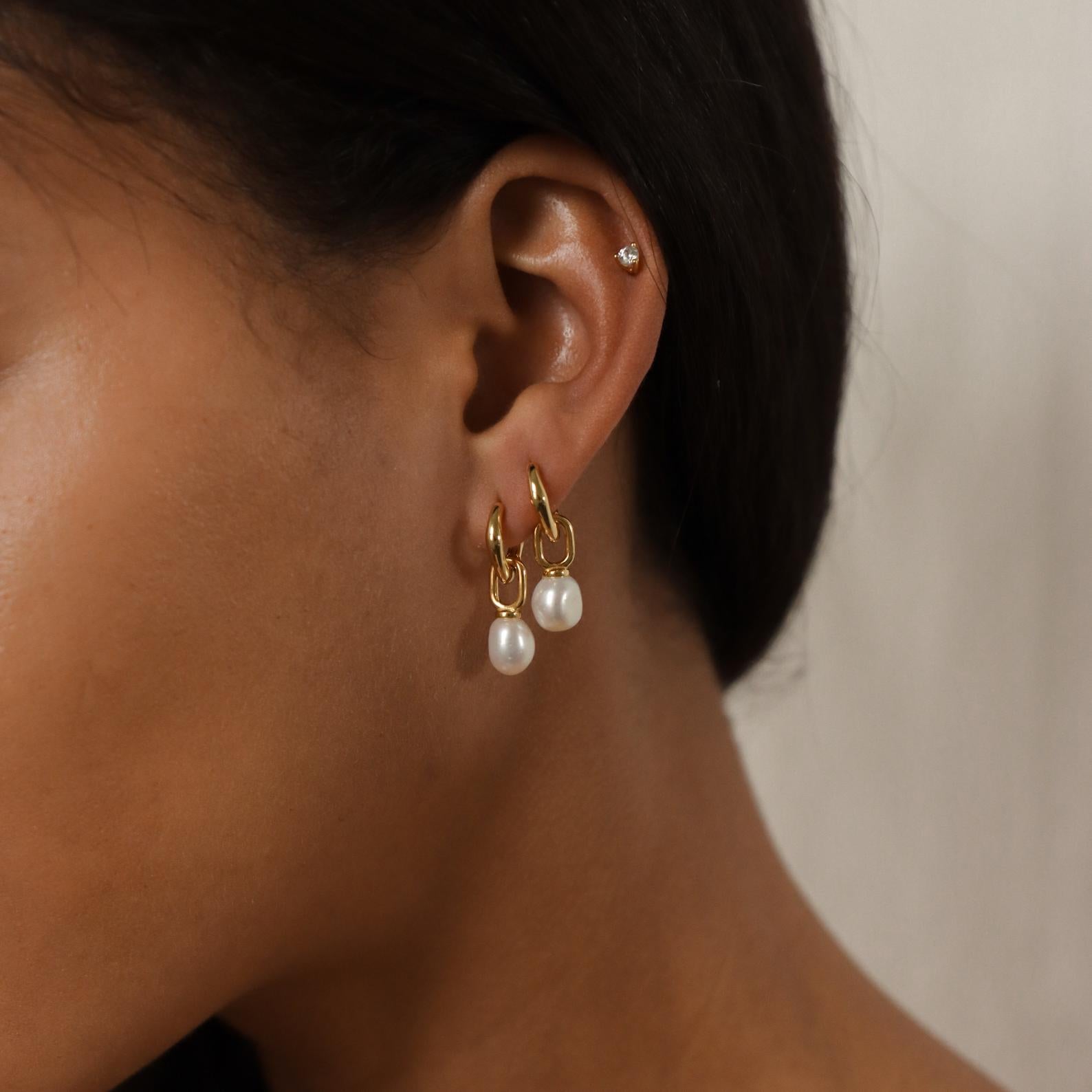 Close-up of a woman's ear wearing Hazel Pearl Hoops—gold hoops with dangling pearls and a small stud in the upper ear, ideal for modern jewelry lovers.