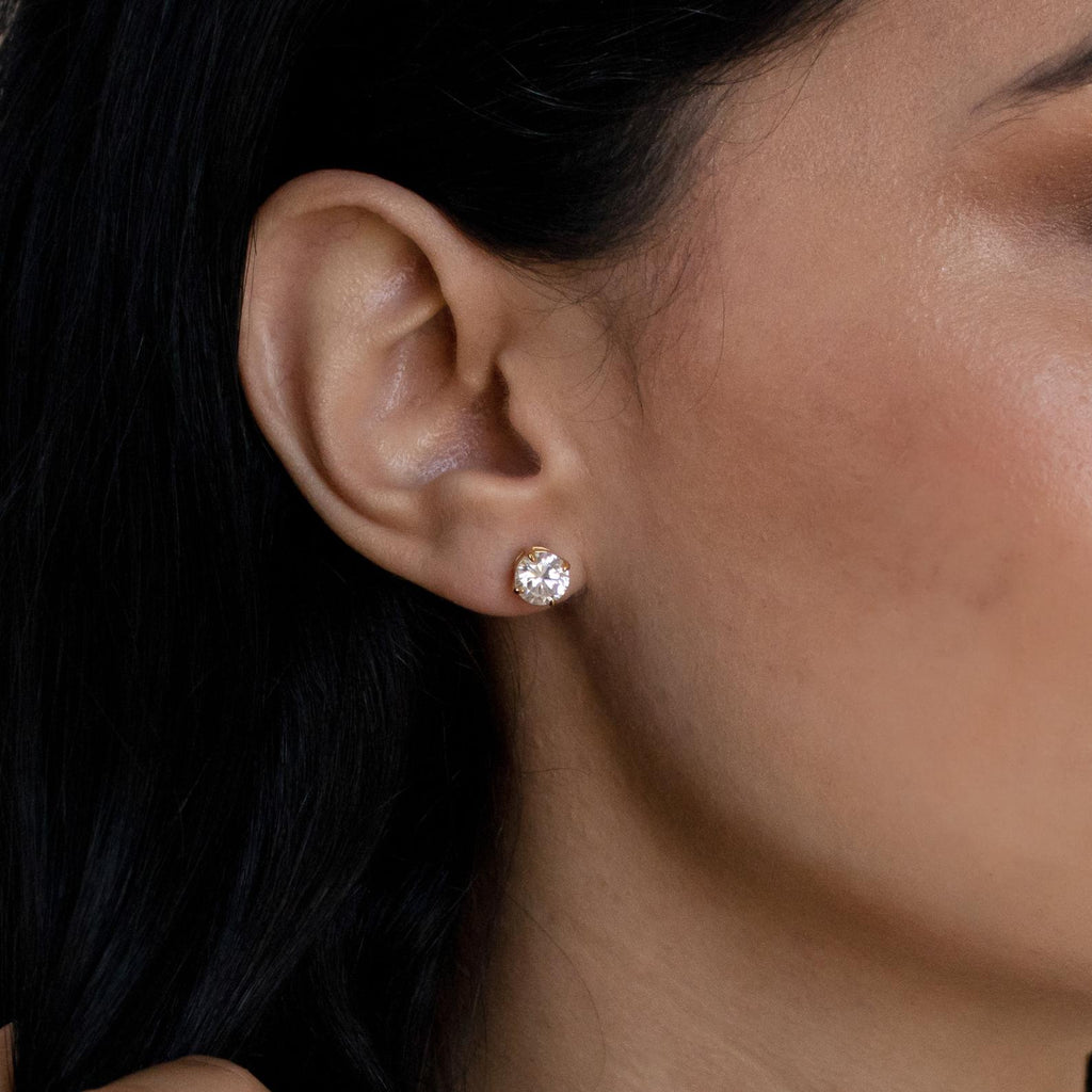 A close-up of a woman's ear adorned with Round Diamond Studs, highlighting the timeless elegance of classic jewelry.