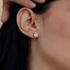 A close-up of a woman's ear adorned with Oval Diamond Studs as she rests her hand on her head—an elegant touch of classic jewelry.