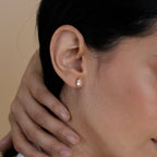 Close-up of a woman’s ear adorned with Classic Marquise Diamond Studs in gold; her hand rests near her neck, showcasing the timeless elegance of these classic diamond earrings.