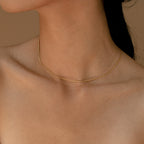 A minimal gold snake chain necklace worn close to the neck against bare skin