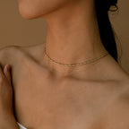 A twisted gold thin snake chain necklace styled tightly around the neck