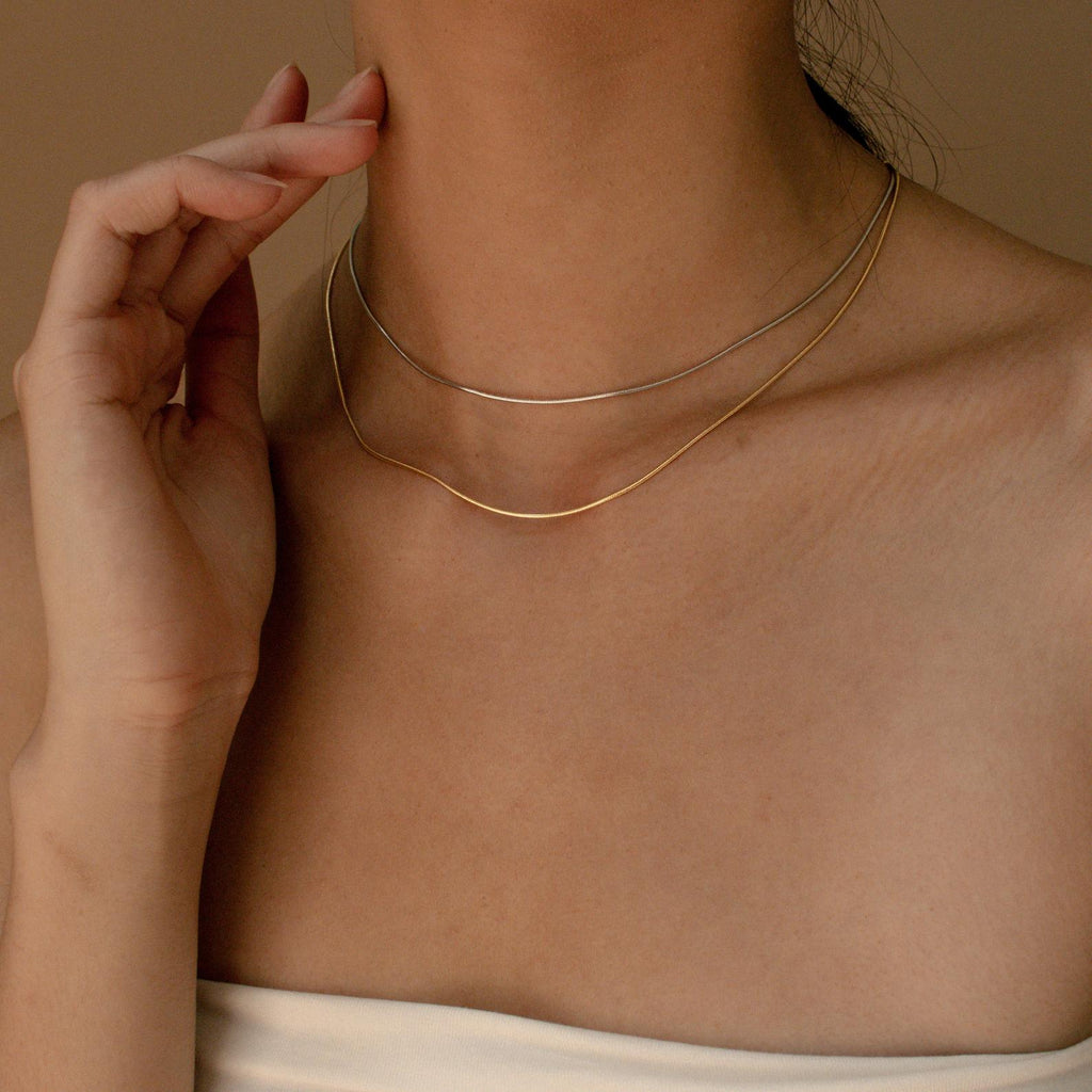  model wearing both the white gold and yellow gold snake chains, showcasing a stacked necklace style.