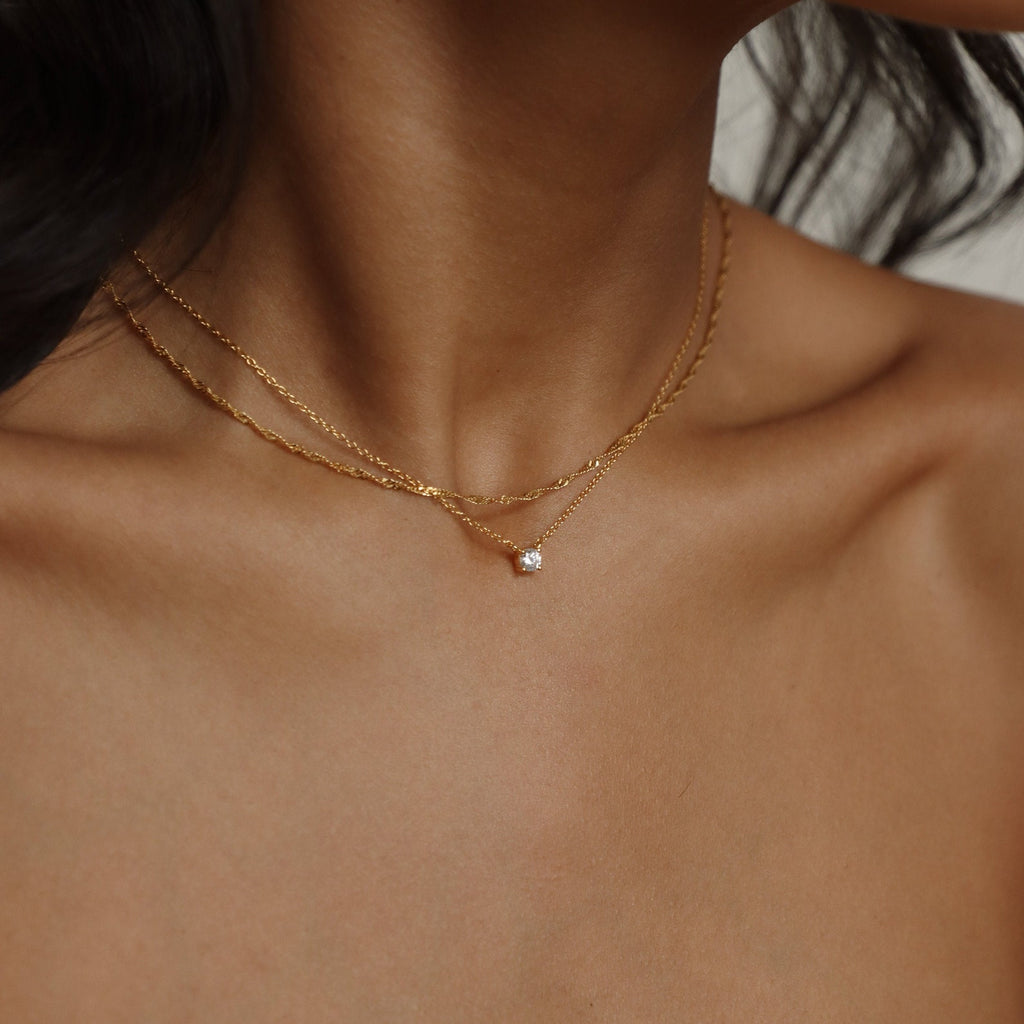 A model layering the Singapore Twist necklace with a small pendant, creating a refined, stacked look.