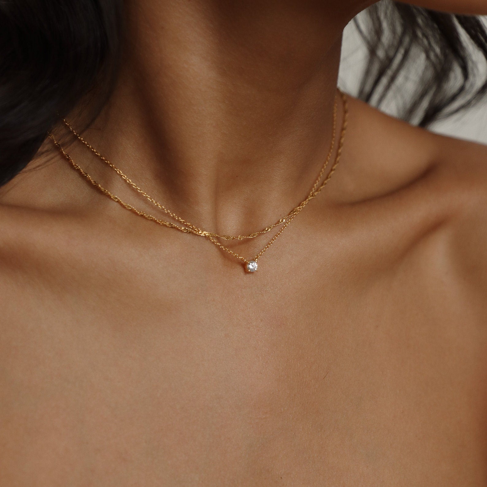 A model layering the Singapore Twist necklace with a small pendant, creating a refined, stacked look.
