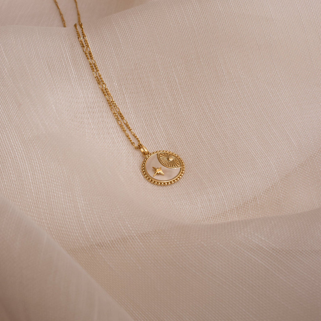 Gabi Coin Necklace with star and eye motifs, shown on soft beige fabric—a perfect minimalist accessory for jewelry lovers.