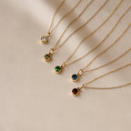 The Custom Birthstone Necklace features five delicate gold chains with round gemstone pendants in assorted colors on a beige backdrop—an ideal personalized jewelry gift or meaningful birthstone keepsake.