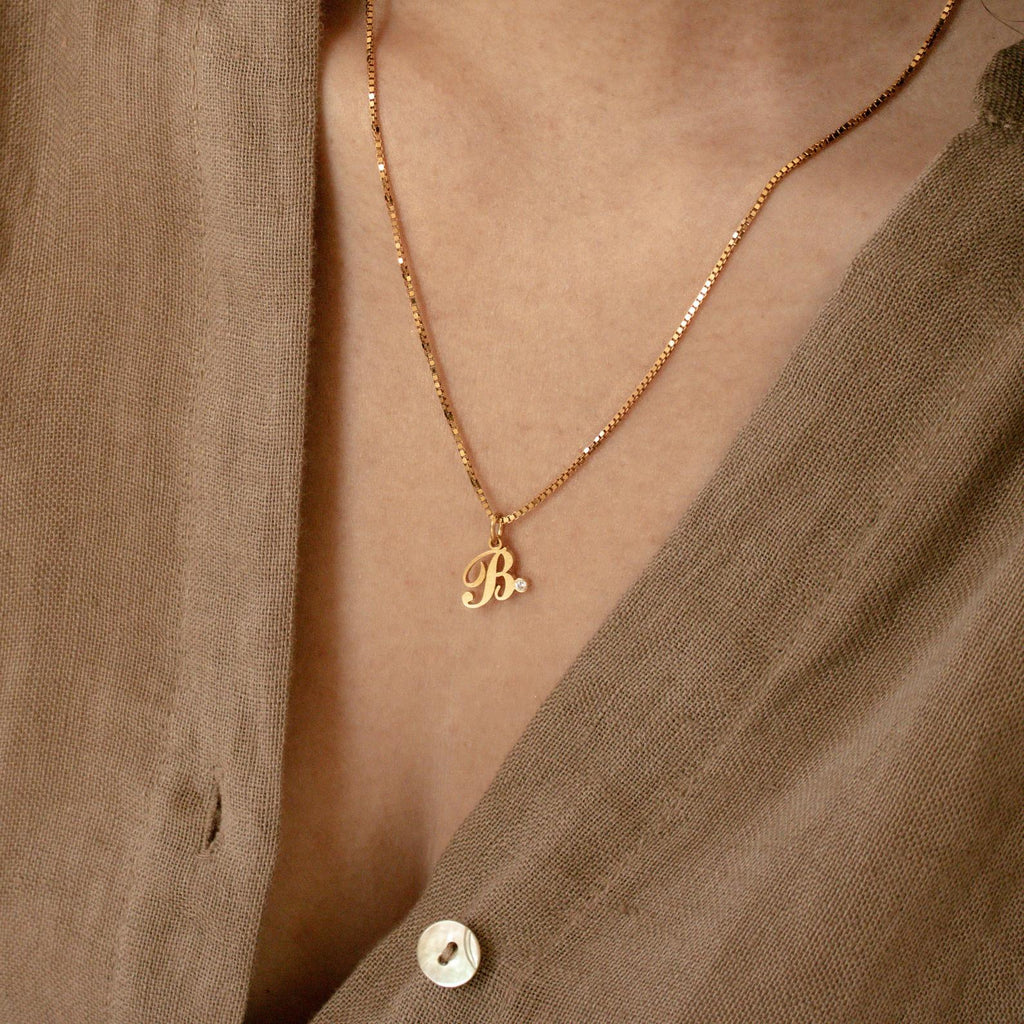 Initial Birthstone Necklace with a B pendant and gem, styled over a brown buttoned shirt—a chic personalized gift or custom monogram accessory for any occasion.