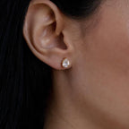 Close-up of a woman's ear wearing Pear Diamond Studs: minimalistic gold earrings featuring a teardrop-shaped clear gemstone, ideal for everyday elegance.