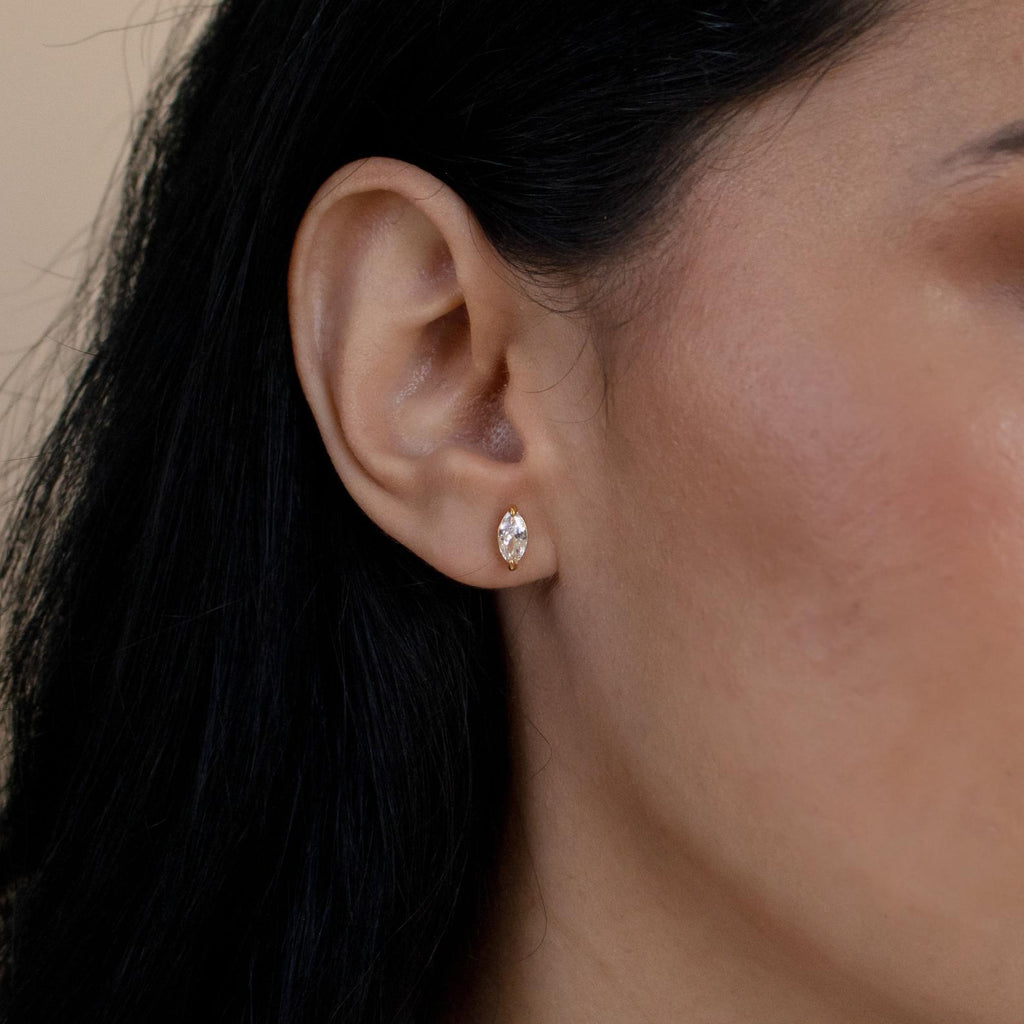 Close-up of a woman's ear wearing Classic Marquise Diamond Studs, small oval-shaped earrings with clear gemstones that capture the timeless beauty of classic diamond jewelry.