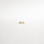 Triangle Diamond Studs—small gold earrings with clear gemstones—add classic elegance to any look. Shown on a plain white background.
