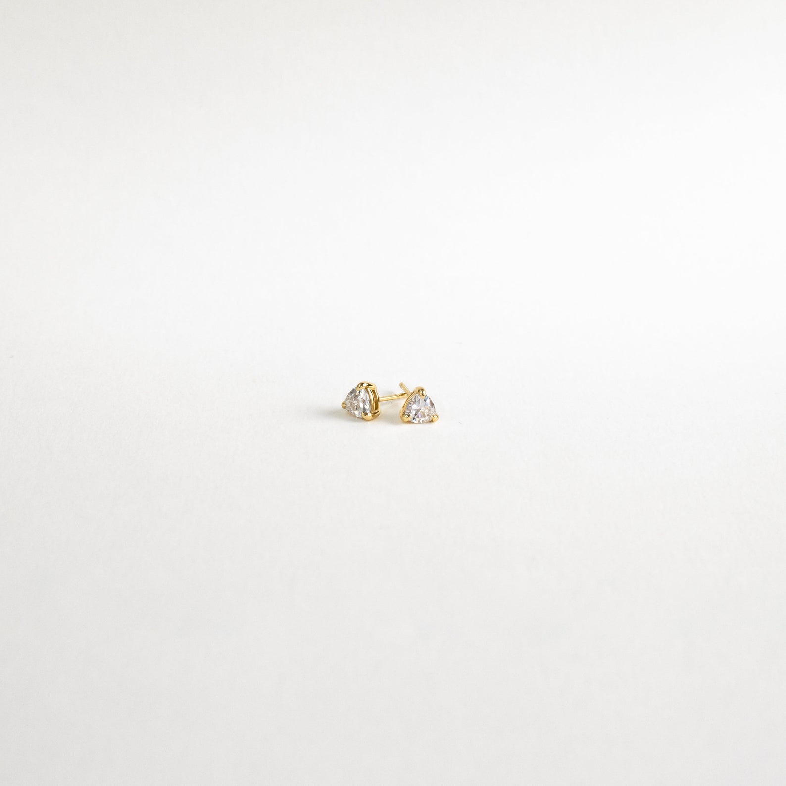 Triangle Diamond Studs—small gold earrings with clear gemstones—add classic elegance to any look. Shown on a plain white background.