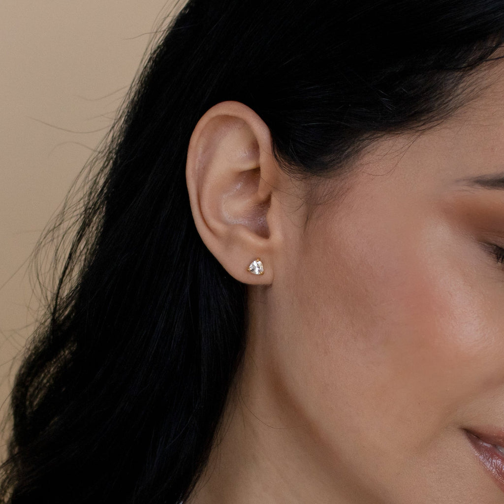 Close-up of a woman's ear adorned with Triangle Diamond Studs—an elegant, modern twist on classic jewelry—set against her dark hair.