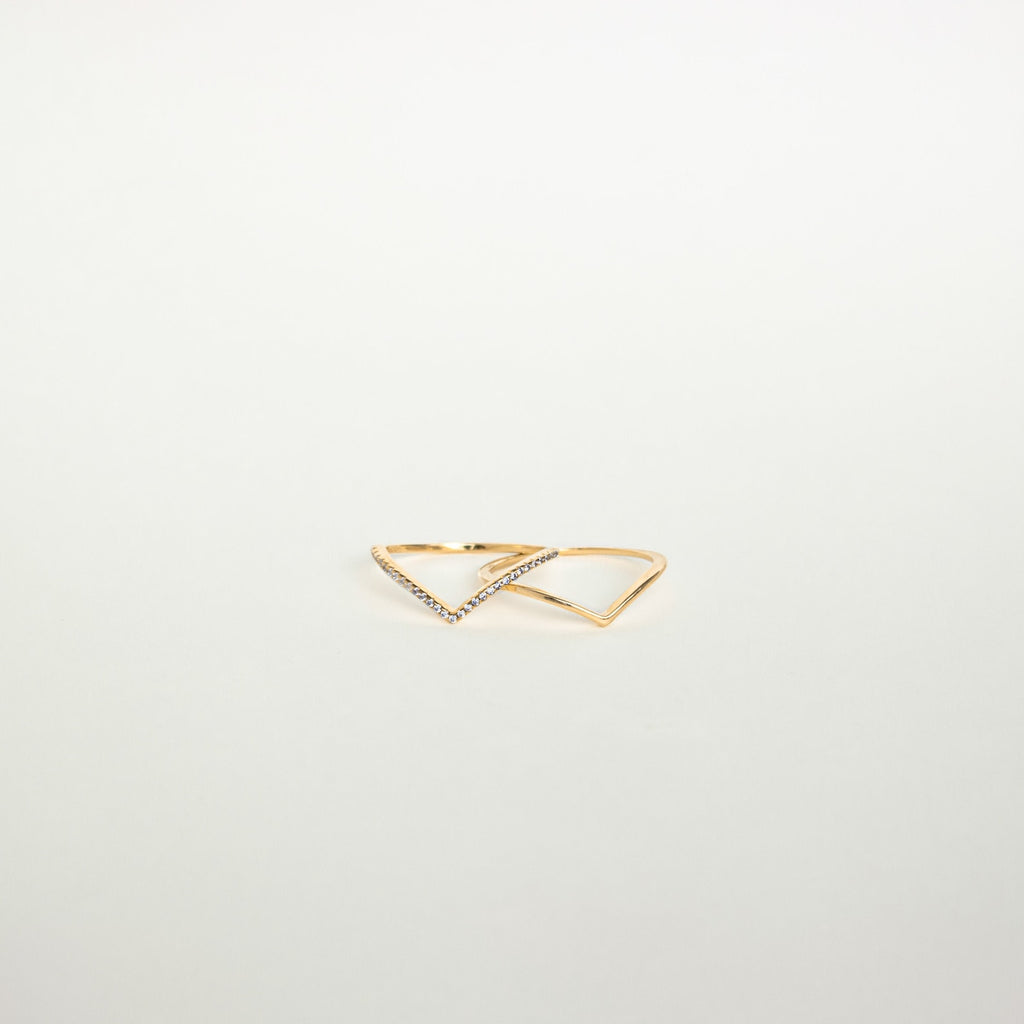 The Curve Stacking Set features two delicate gold rings with open triangle designs, one accented by small gemstones, offering a modern touch to your favorite ring stack.