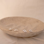 Marquise diamond stud earrings in 18K gold and sterling silver with pave-set diamonds, displayed on a beige stone dish with.