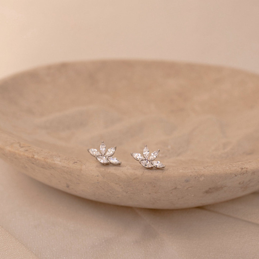 Marquise diamond stud earrings with clustered pear-shaped stones set in 18K gold, displayed on a carved beige stone dish.
