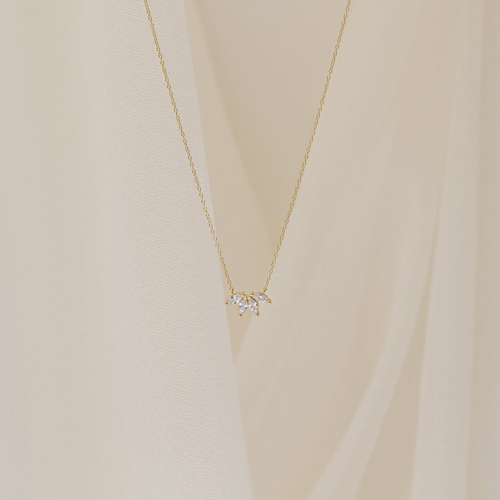 A delicate gold chain necklace featuring a small cluster of marquise-cut clear stones arranged like petals.