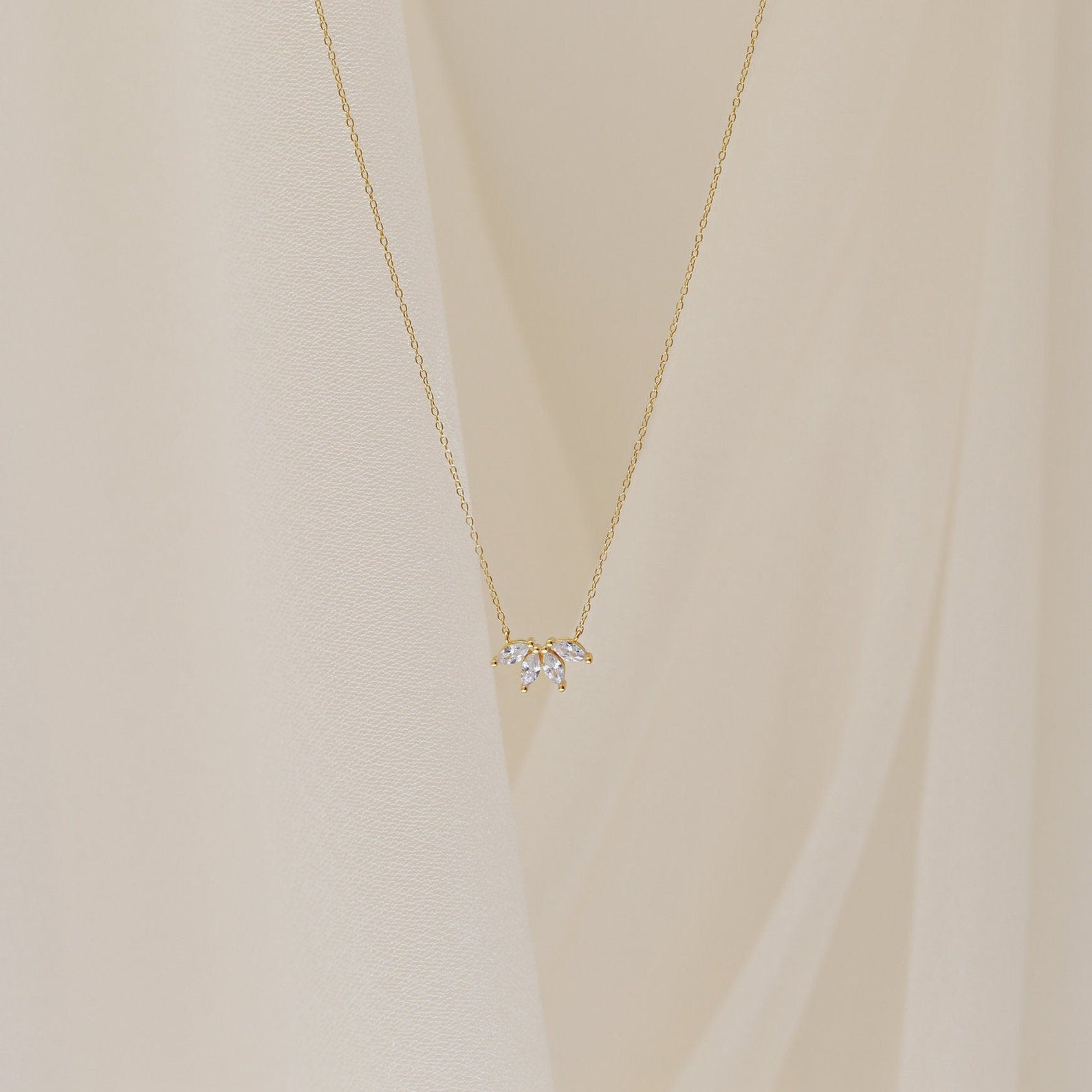 A delicate gold chain necklace featuring a small cluster of marquise-cut clear stones arranged like petals.