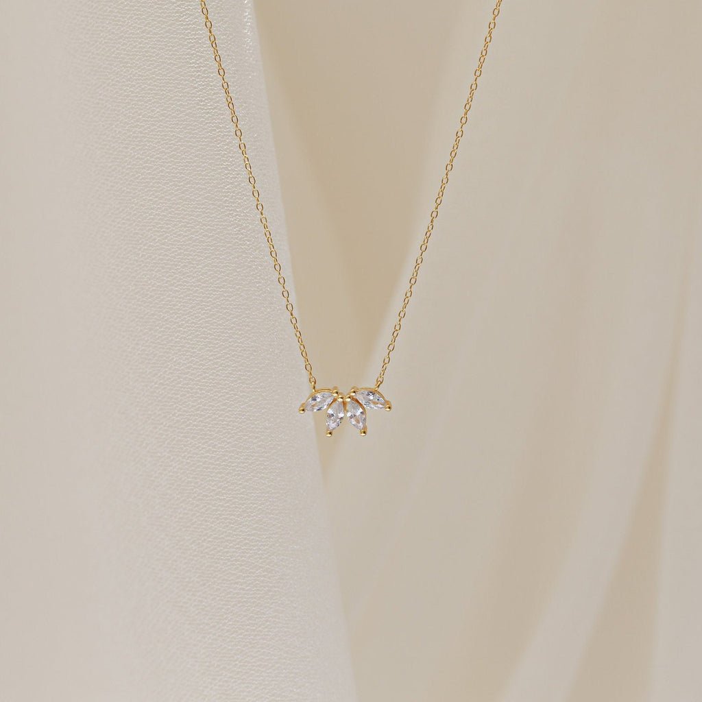 A delicate gold chain necklace featuring a small cluster of marquise-cut clear stones arranged like petals.
