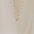 A delicate gold chain necklace featuring a small cluster of marquise-cut clear stones arranged like petals.