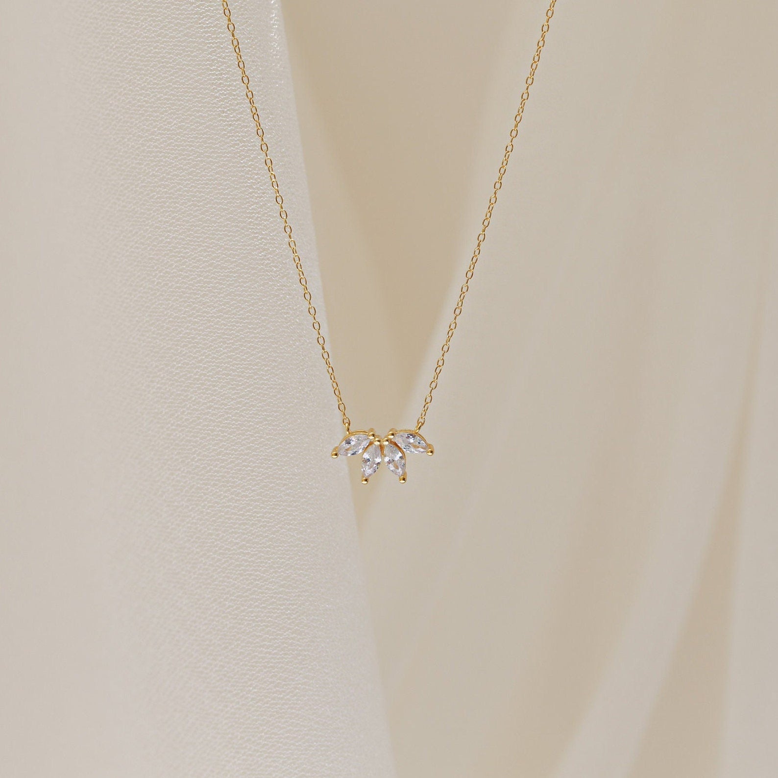A delicate gold chain necklace featuring a small cluster of marquise-cut clear stones arranged like petals.